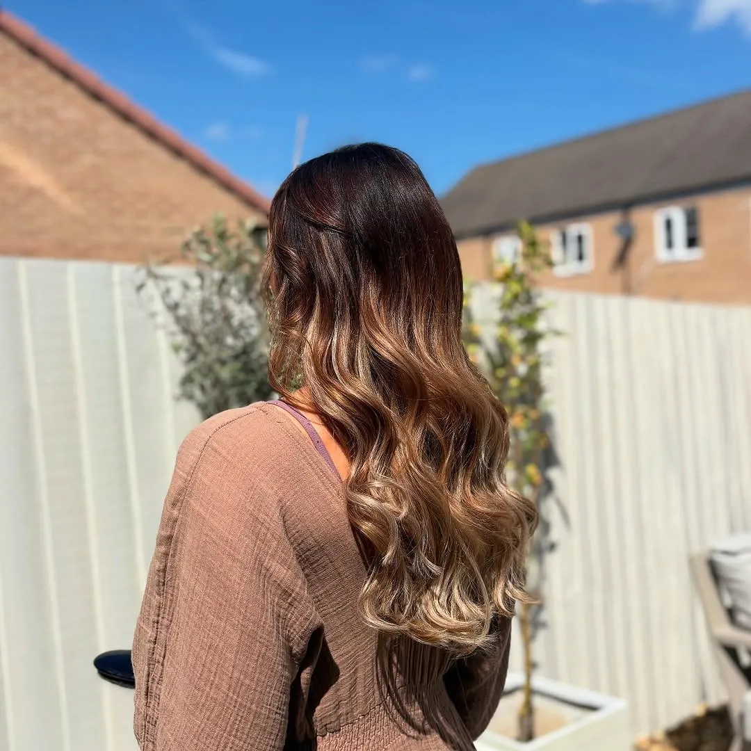 Long balayage Hollywood waves catching bright sunshine, seen from behind.